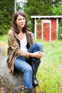 Åsa Avdic porträtt sitter på en sten