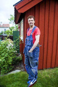 Micke Leijnegard står vid stugans husknut