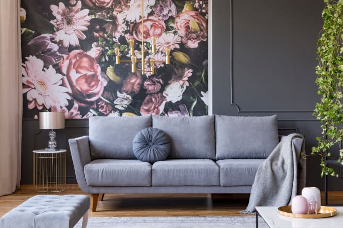 Blanket on grey couch in living room interior with flowers wallp