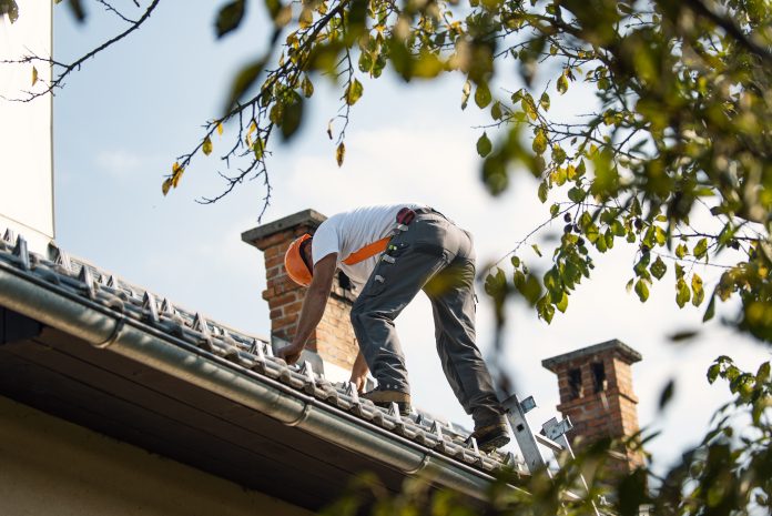 Roofer measuring chimney on roof top