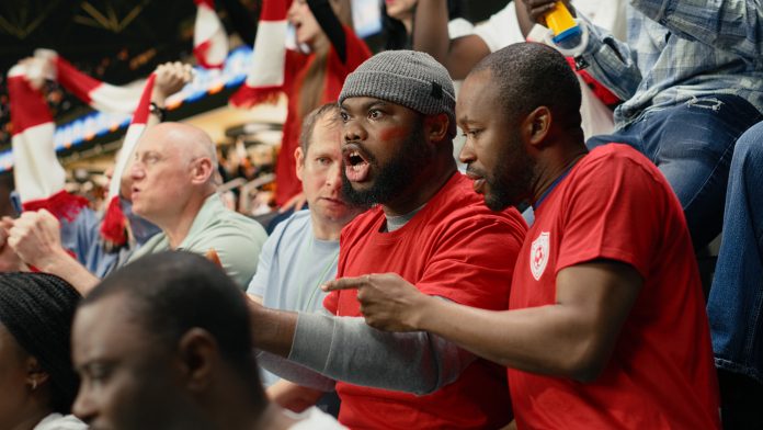 Passionate black fans following live betting odds on smartphone